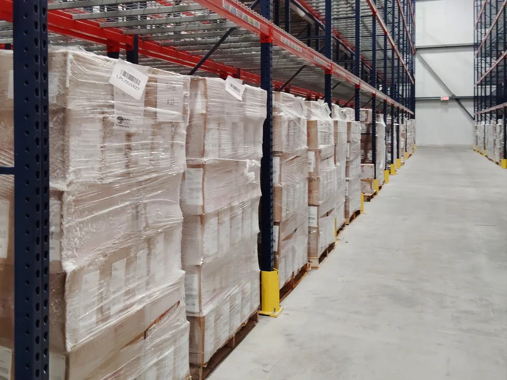 Frost-covered shrink-wrapped pallets in the freezer racking at the Louisville facility, with the aisle receding behind
