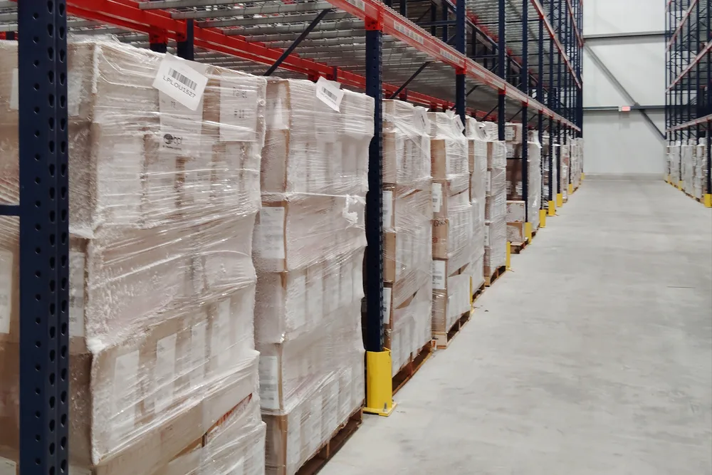 Frost-covered shrink-wrapped pallets on the A level of freezer racking at the Louisville facility, with the freezer aisle receding behind
